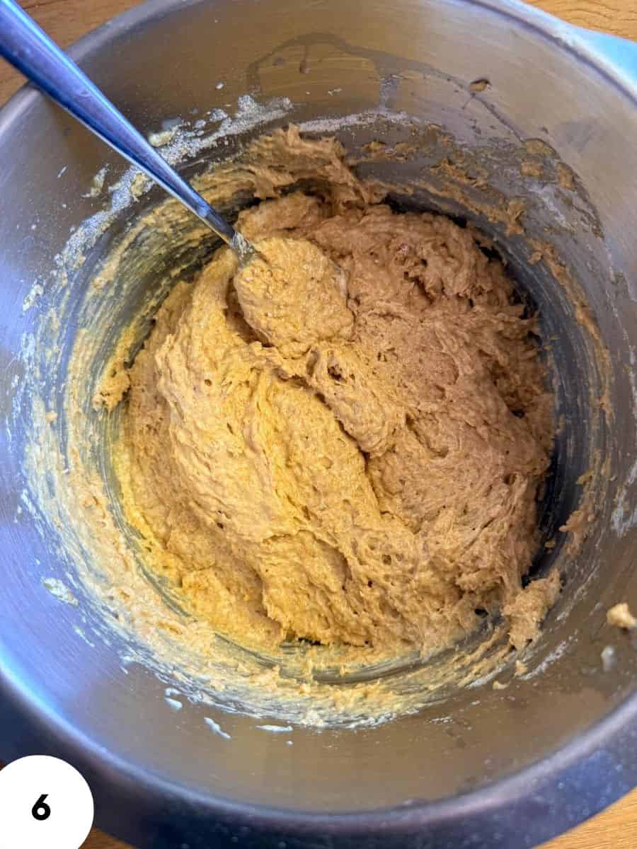 Mixing Einkorn banana bread batter in a metal bowl with a spoon.