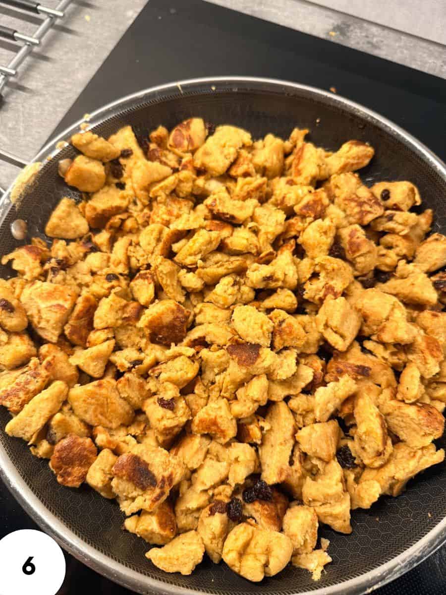 Golden crispy homemade croutons on a black plate for salads or soups.
