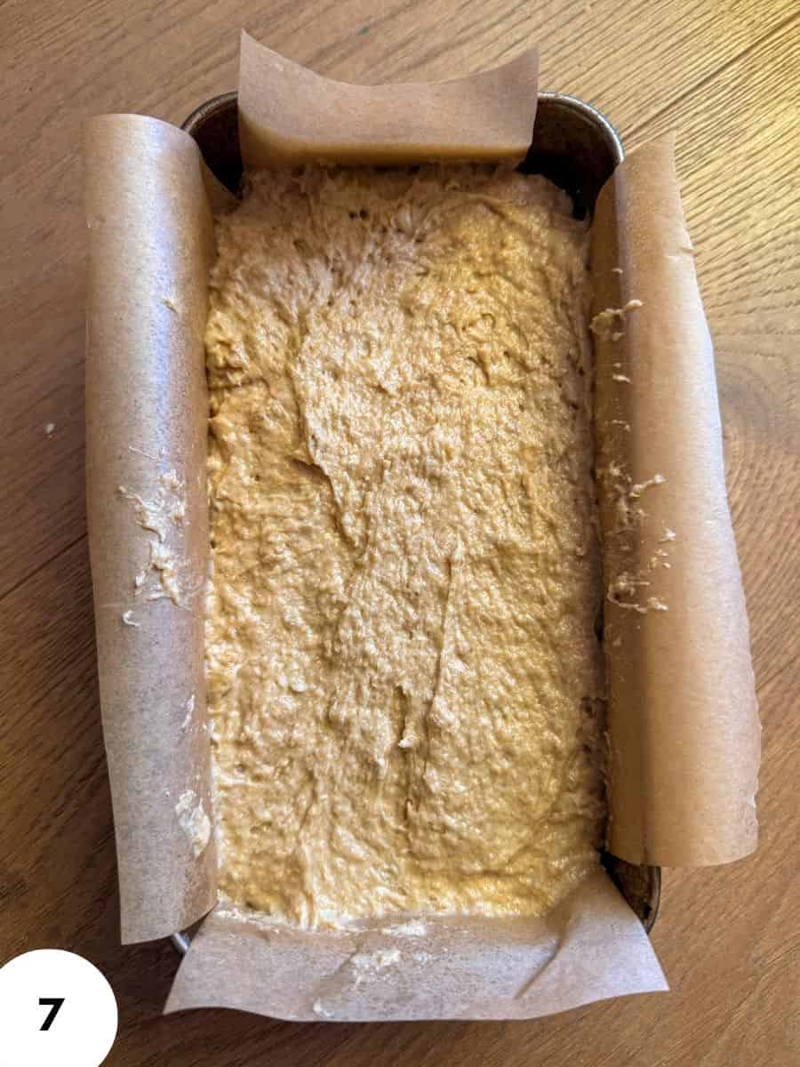 Unbaked banana bread in a parchment-lined baking pan with parchment paper edges.