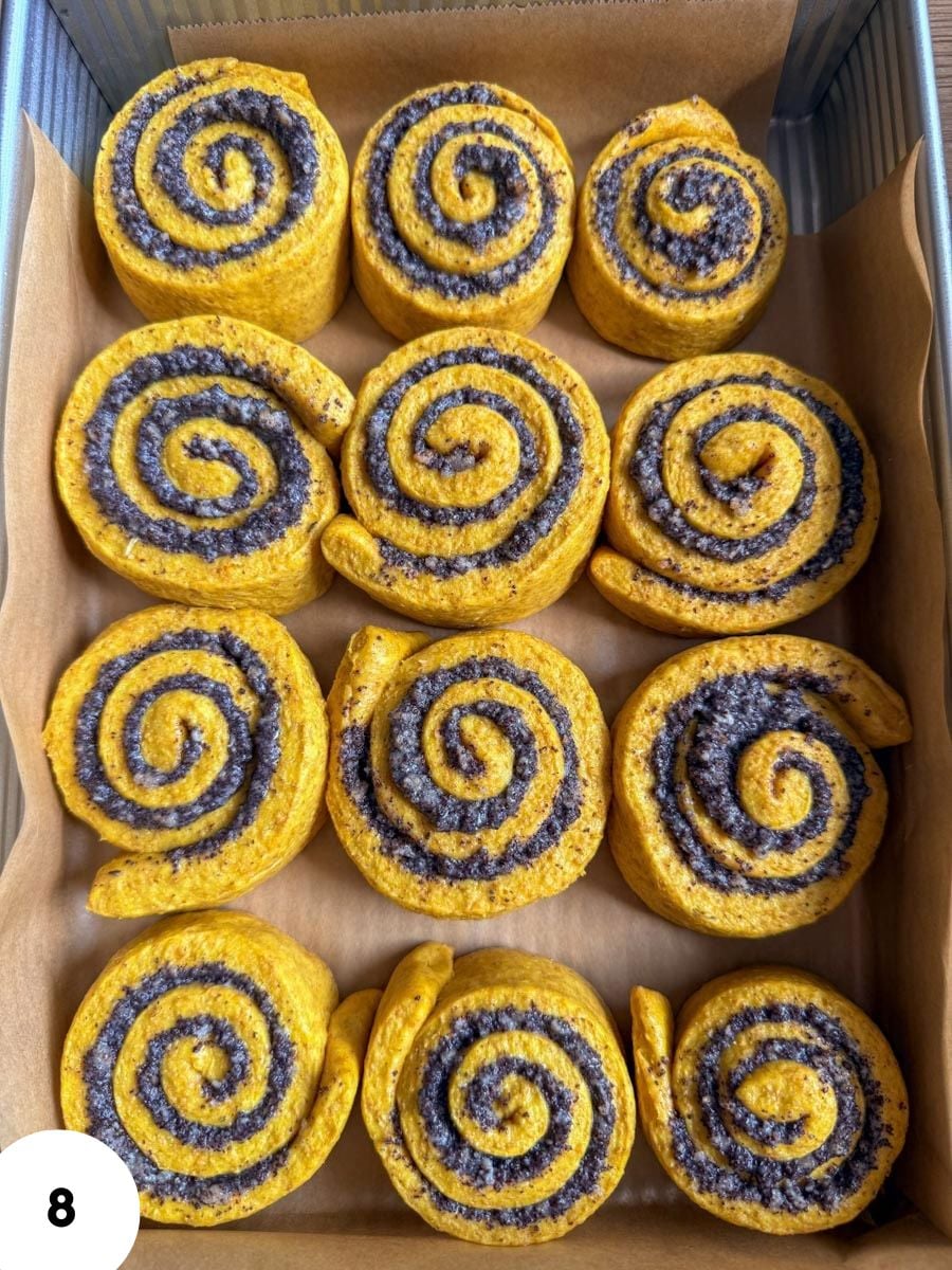 Freshly baked cinnamon rolls with purple swirl filling in a baking tray.