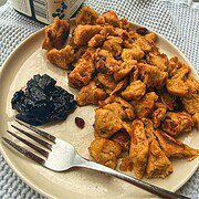 Close-up of homemade chicken and fruit fritters with a side of jam on a plate.