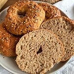Freshly baked bagels with sesame seeds on top, sliced to show soft interior.