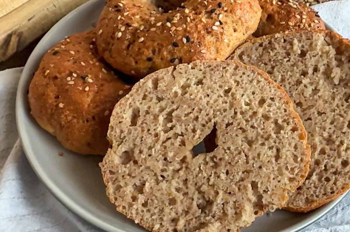 Freshly baked bagels with sesame seeds on top, sliced to show soft interior.