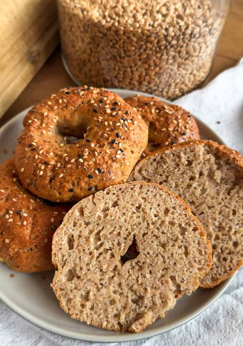 Freshly baked bagels with sesame seeds on top, sliced to show soft interior.