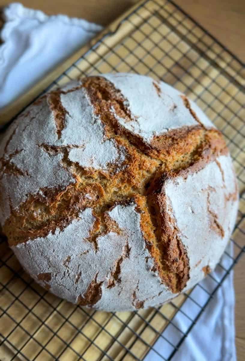 Close-up of a round sourdough bread with a crusty top and scoring marks.
