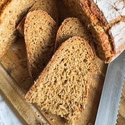 Freshly baked bread with slices on a wooden cutting board.