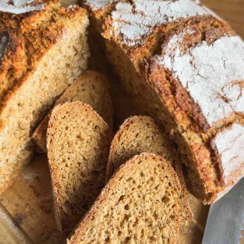 Freshly baked bread with slices on a wooden cutting board.