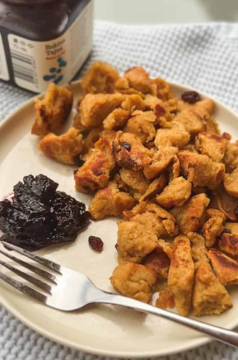 Close-up of crispy chicken pieces with cranberry sauce on a white plate.