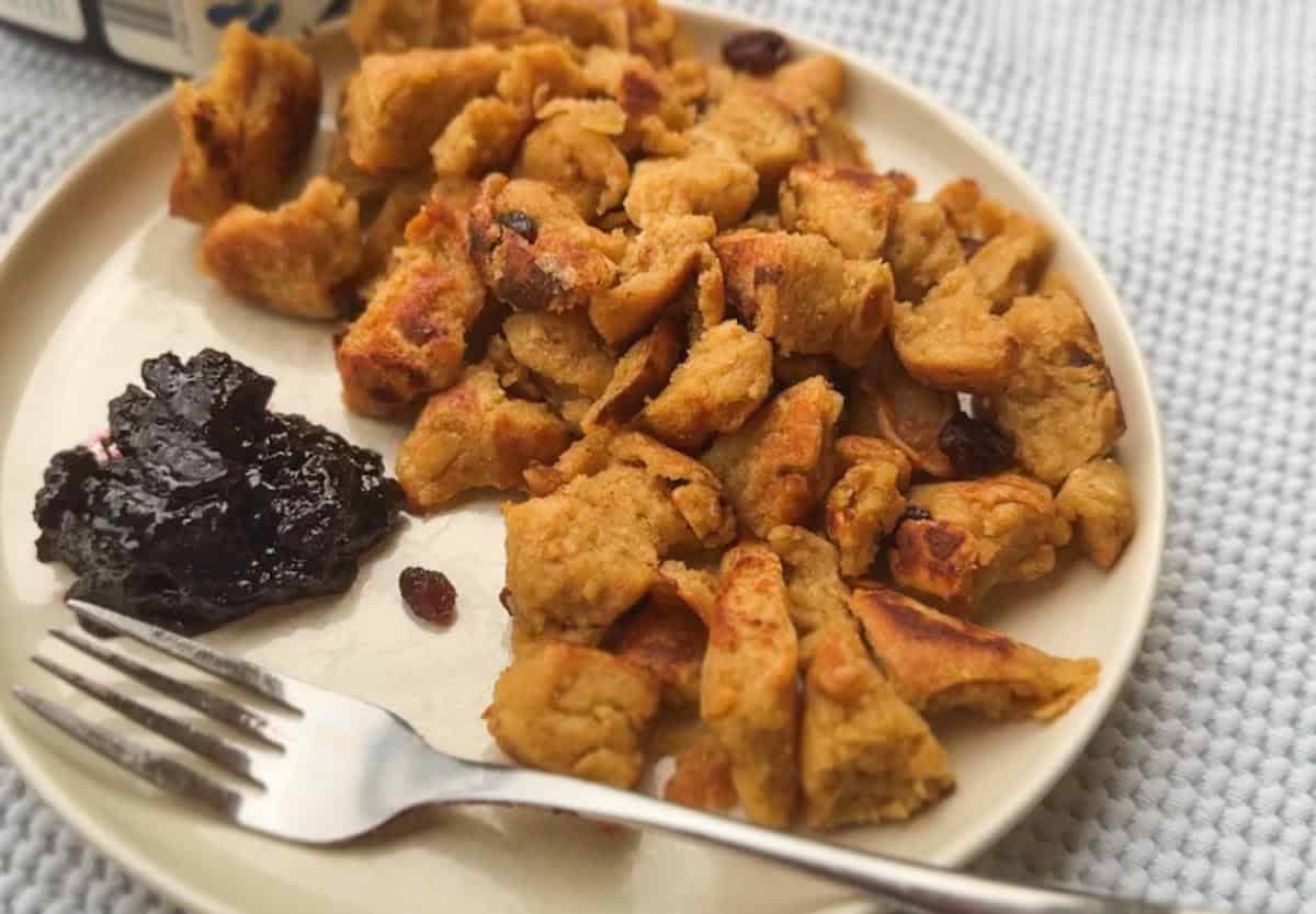 Homemade chicken and cranberry stuffing served on a white plate with a fork.
