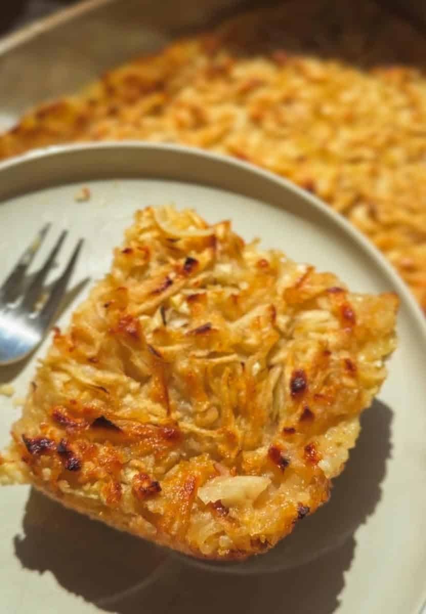 Close-up of a slice of coconut macaroon pie on a plate with a fork.