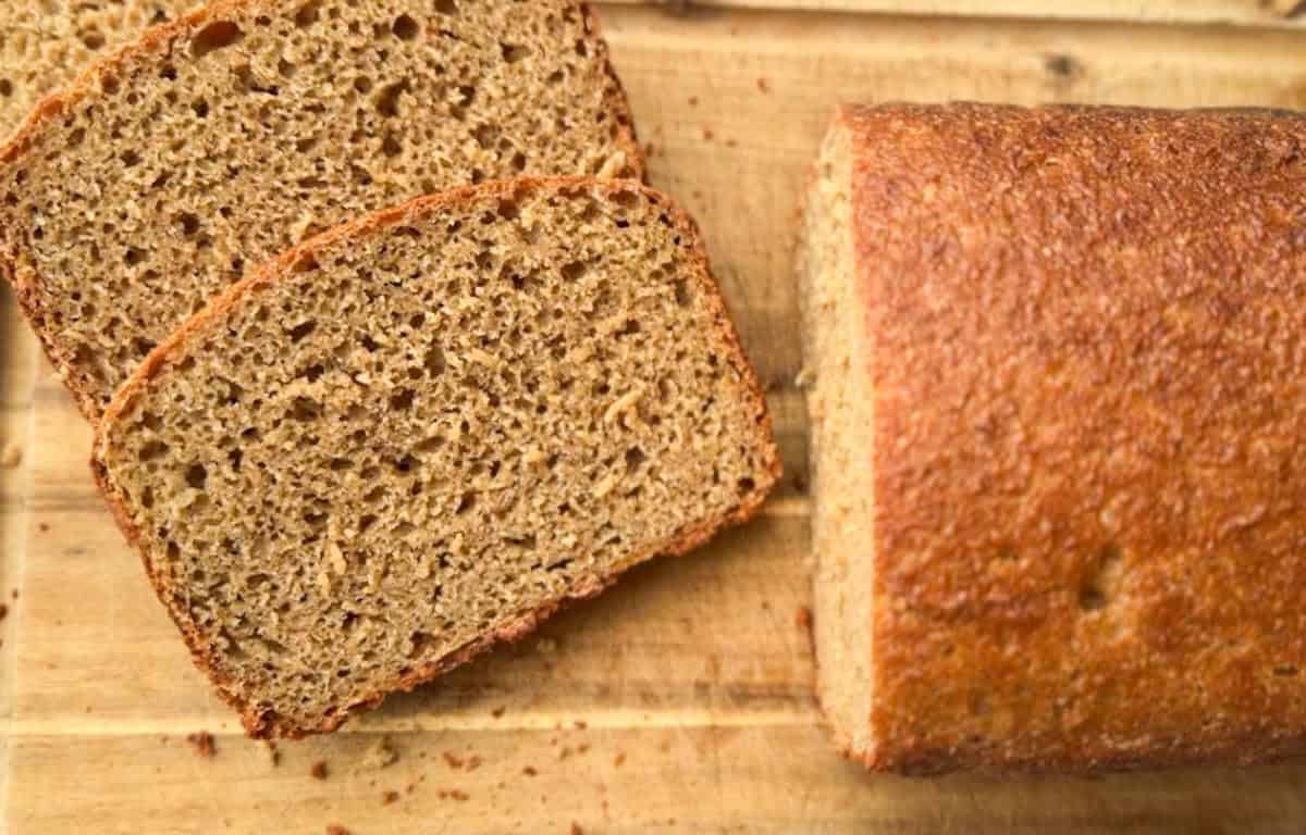 Freshly baked whole wheat bread slices on a wooden surface.