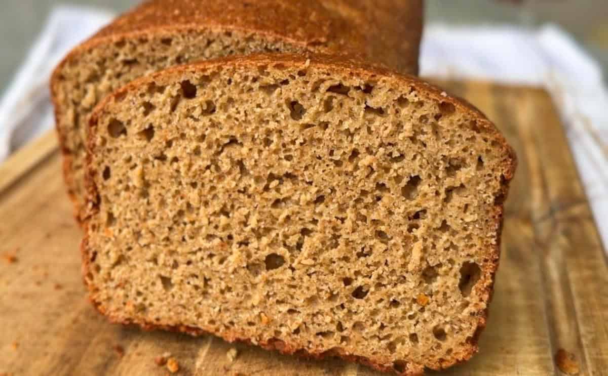 Freshly baked whole wheat bread loaf on a wooden cutting board.