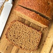 Freshly baked banana bread on a wooden cutting board with a bread knife.