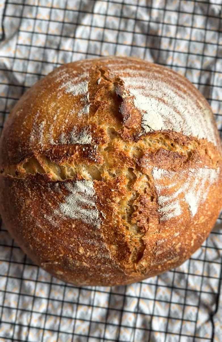 Golden brown bread with a cracked crust on a cooling rack.