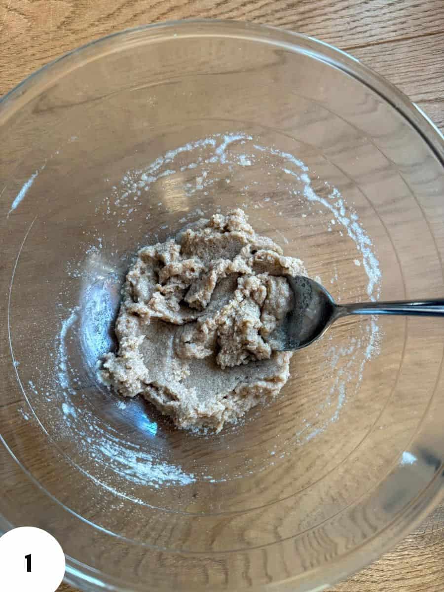 Dough mixture for bread or pastry in a glass bowl with a spoon.