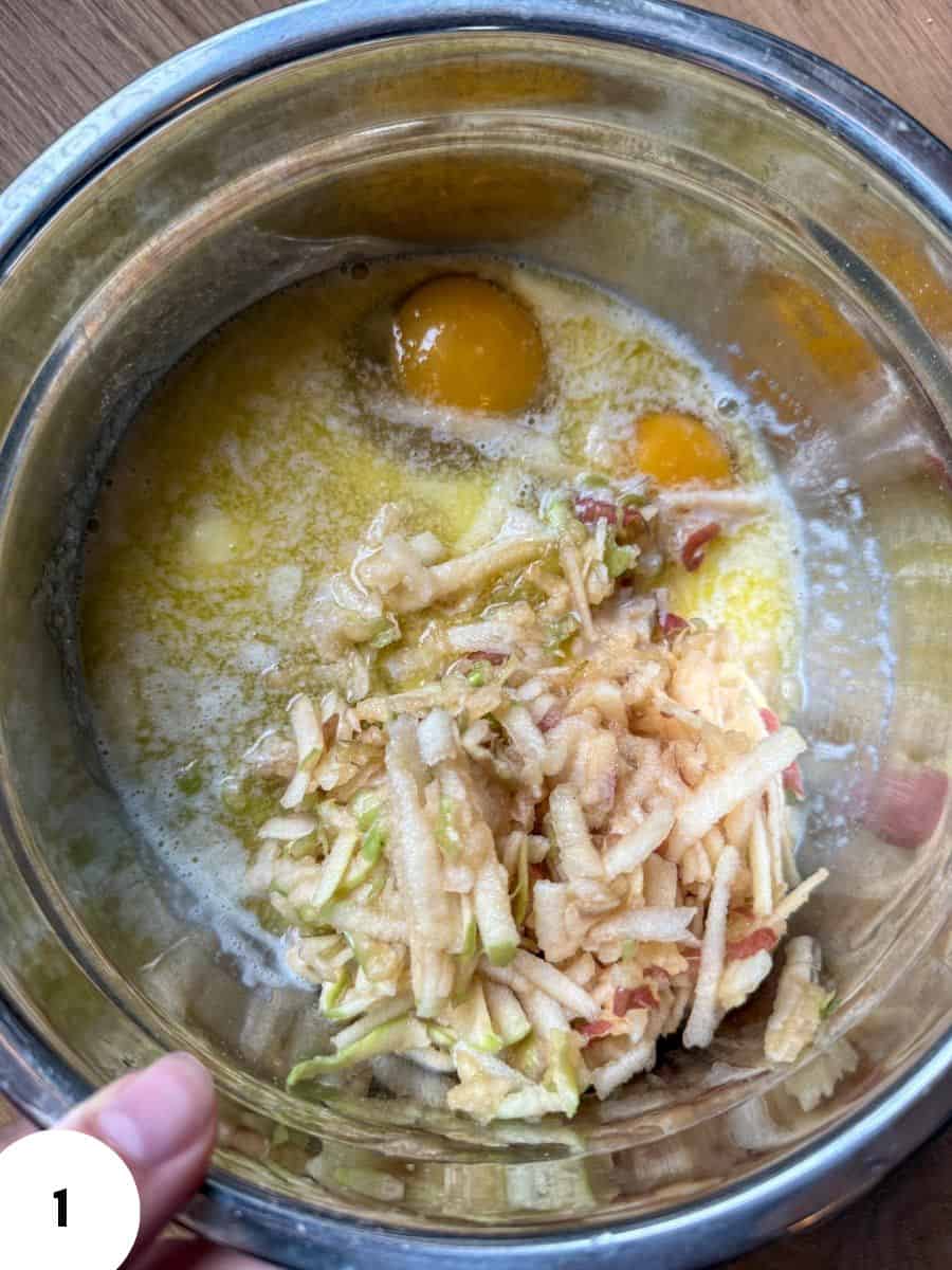 Mixing eggs and shredded dough in a metal bowl for bread making.