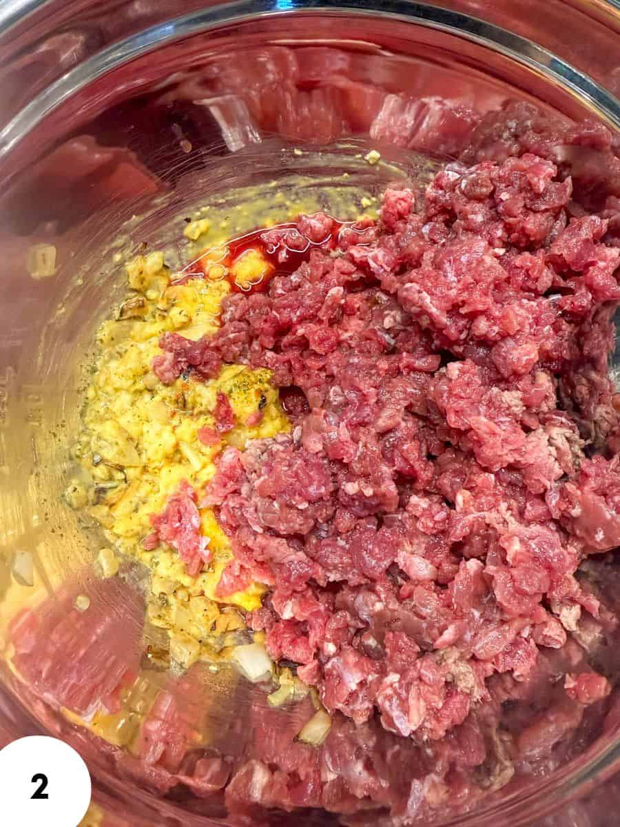 Ground beef with minced onion and egg in a mixing bowl for folding.