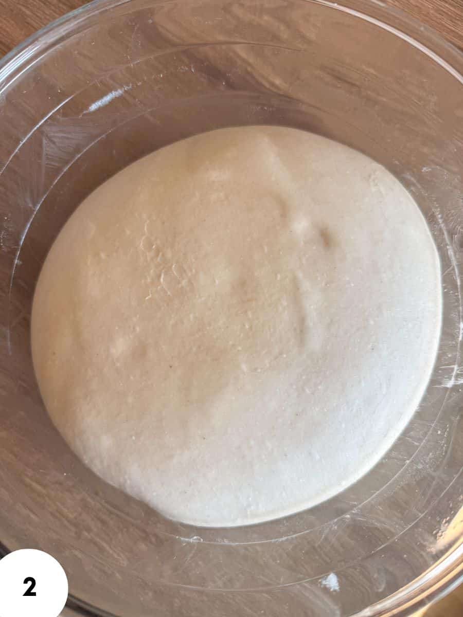 Dough ball in clear bowl ready for resting and folding.
