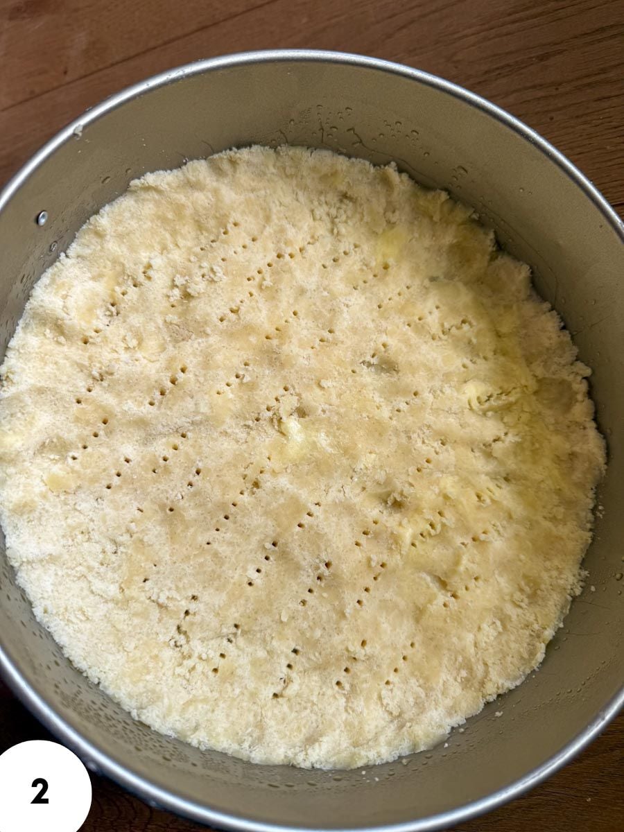 Unbaked bread dough in a round baking pan ready for proofing.