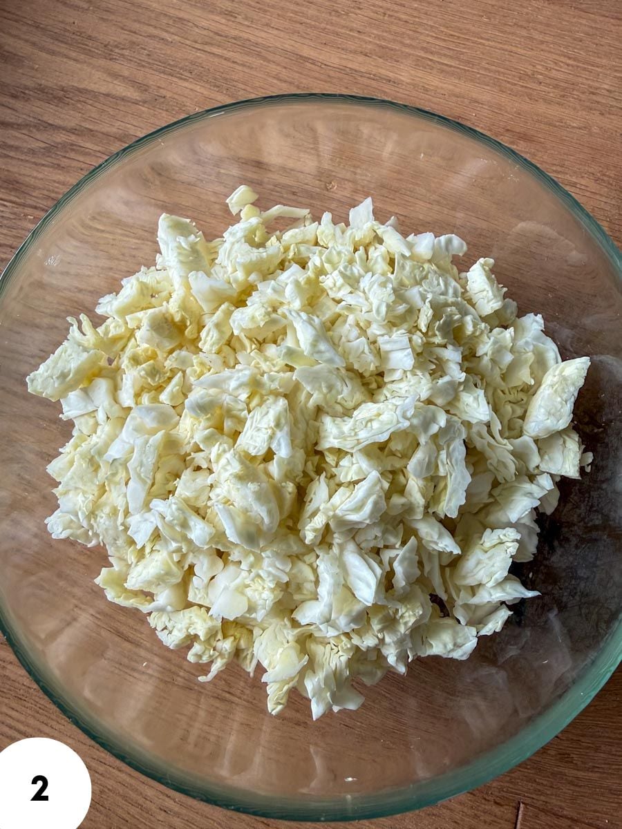 Chopped white cabbage in a glass bowl for bread dough preparation.