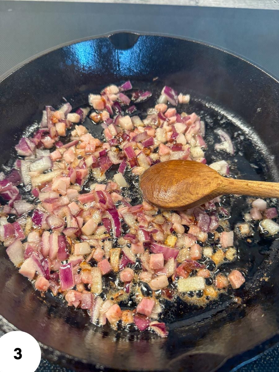 Chopped red onions sautéing in a skillet for bread dough preparation.