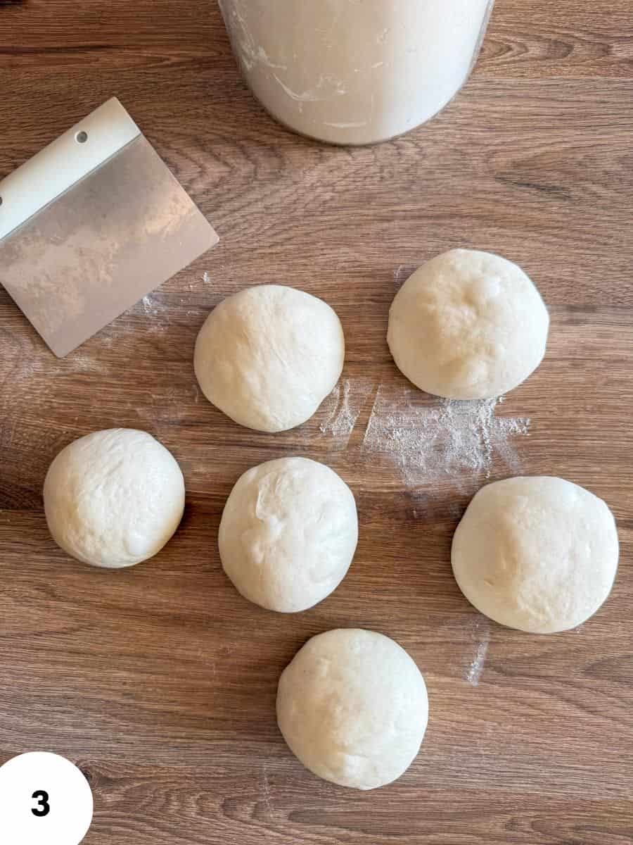 Dough balls arranged on a wooden surface for stretching and folding technique.