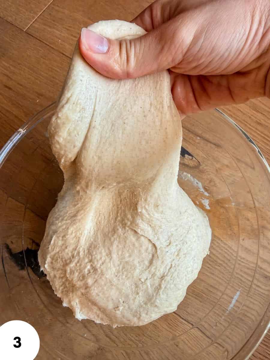 Hand performing stretch and fold dough for bread baking.