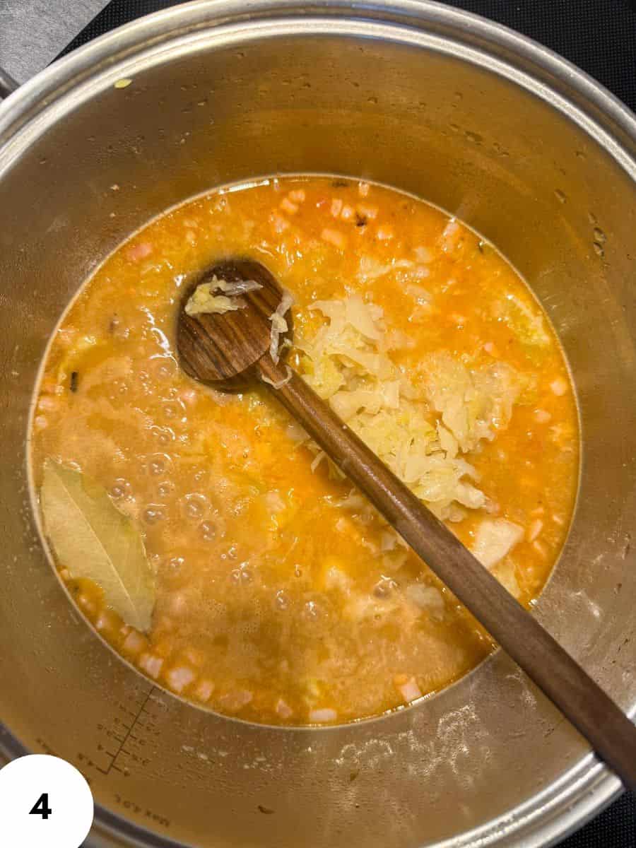 Stovetop pot with orange soup and chopped vegetables being stirred.