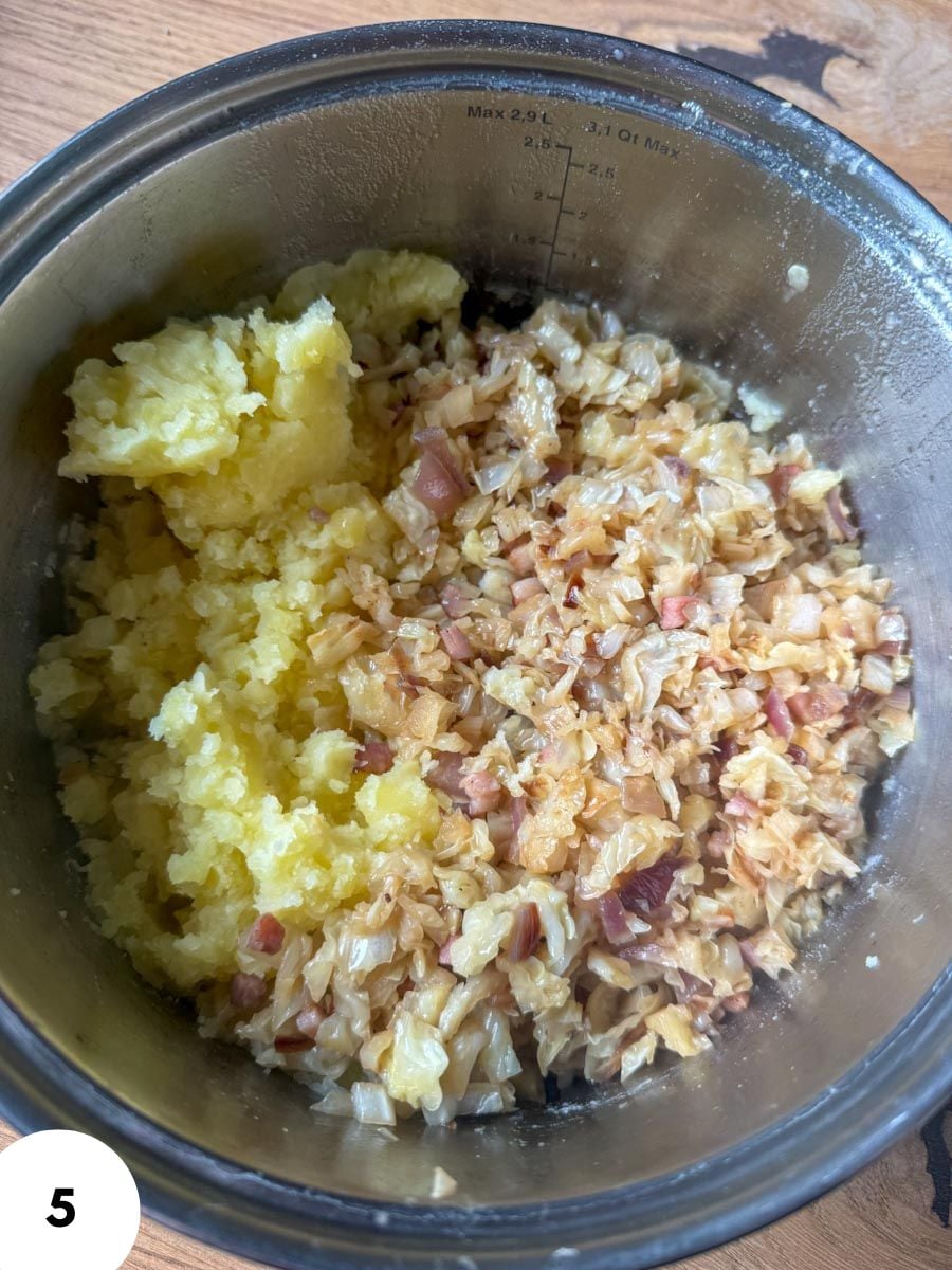 Mixed dough with mashed potatoes and chopped ingredients in a metal bowl.
