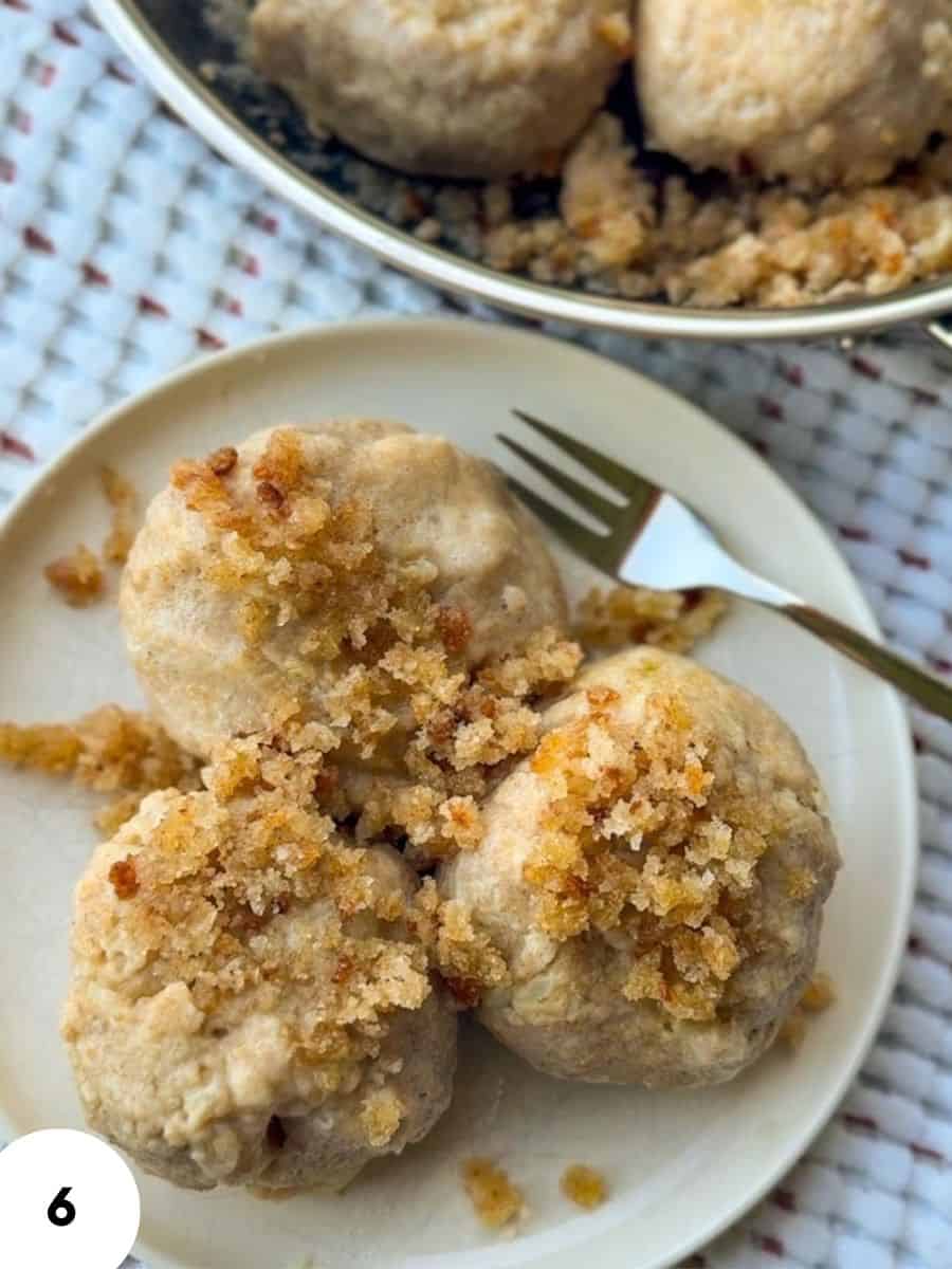 Close-up of baked meatballs with breadcrumb crust on a white plate.