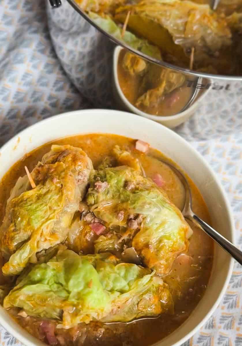 Stunning cabbage rolls simmering in broth with diced ham.