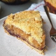 Close-up of a slice of homemade fruit pie with crumble topping on a white plate.