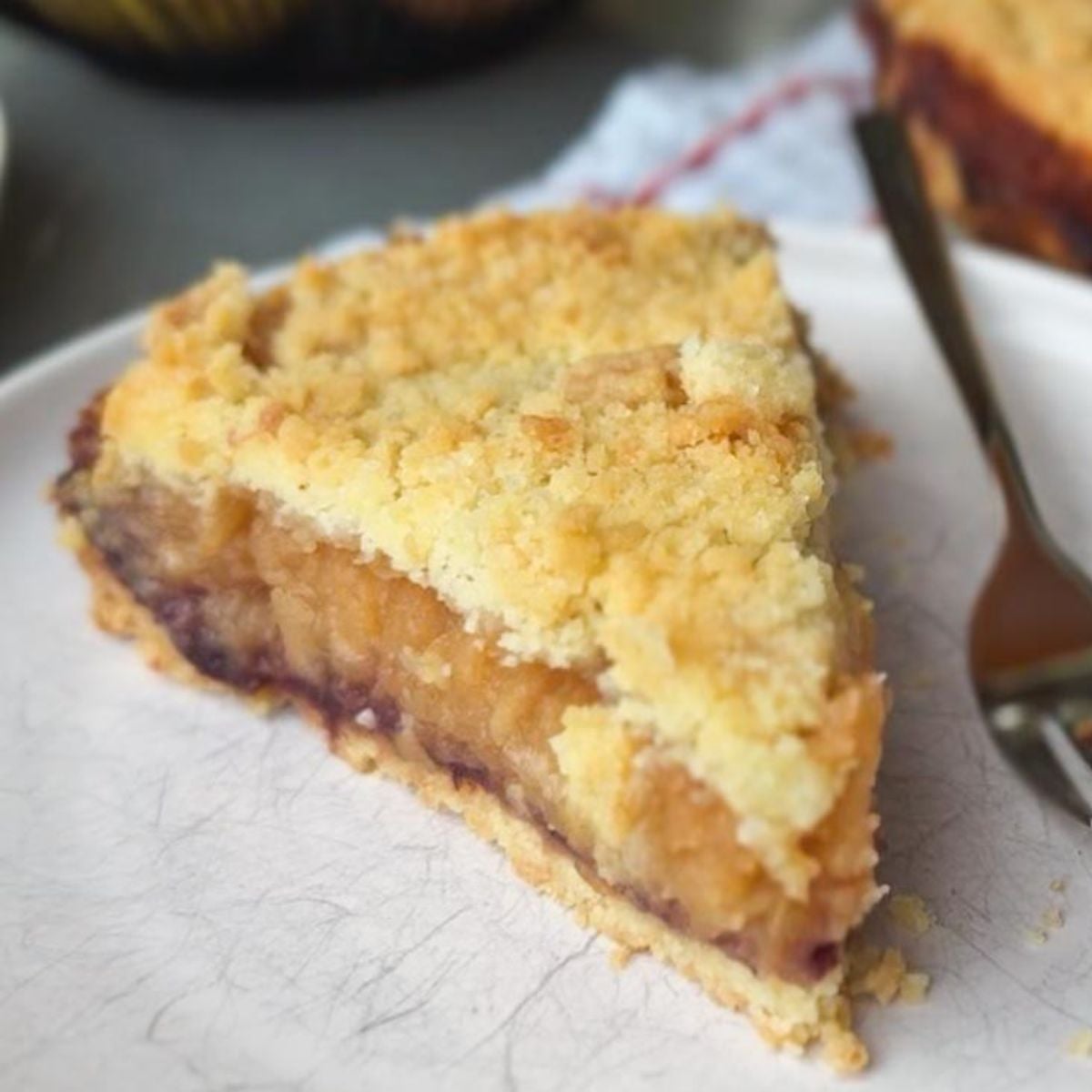 Close-up of a slice of homemade fruit pie with crumble topping on a white plate.