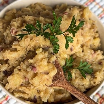 Creamy mashed potatoes garnished with parsley and herbs.