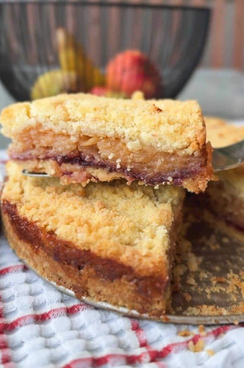 Close-up of a slice of homemade fruit pie with crumble topping on a cake stand.