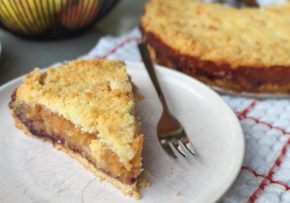 Slice of apple pie with crumble topping on a white plate.