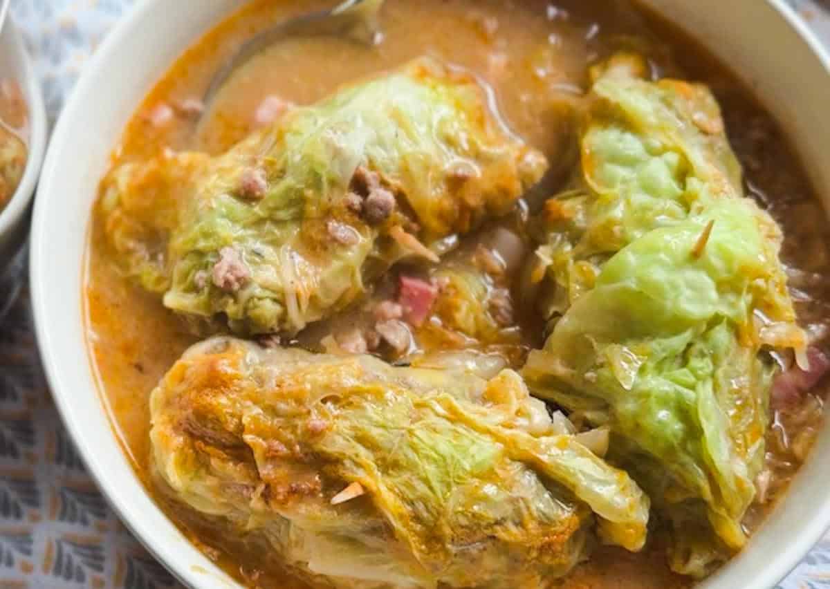 Stovetop cabbage rolls in savory stew with colorful vegetables.