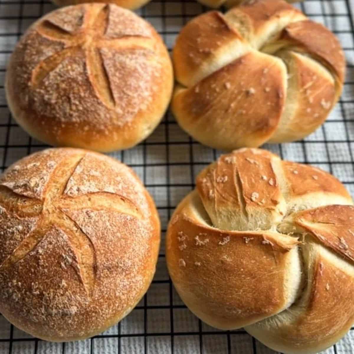 Fresh baked bread rolls with scoring on a cooling rack.