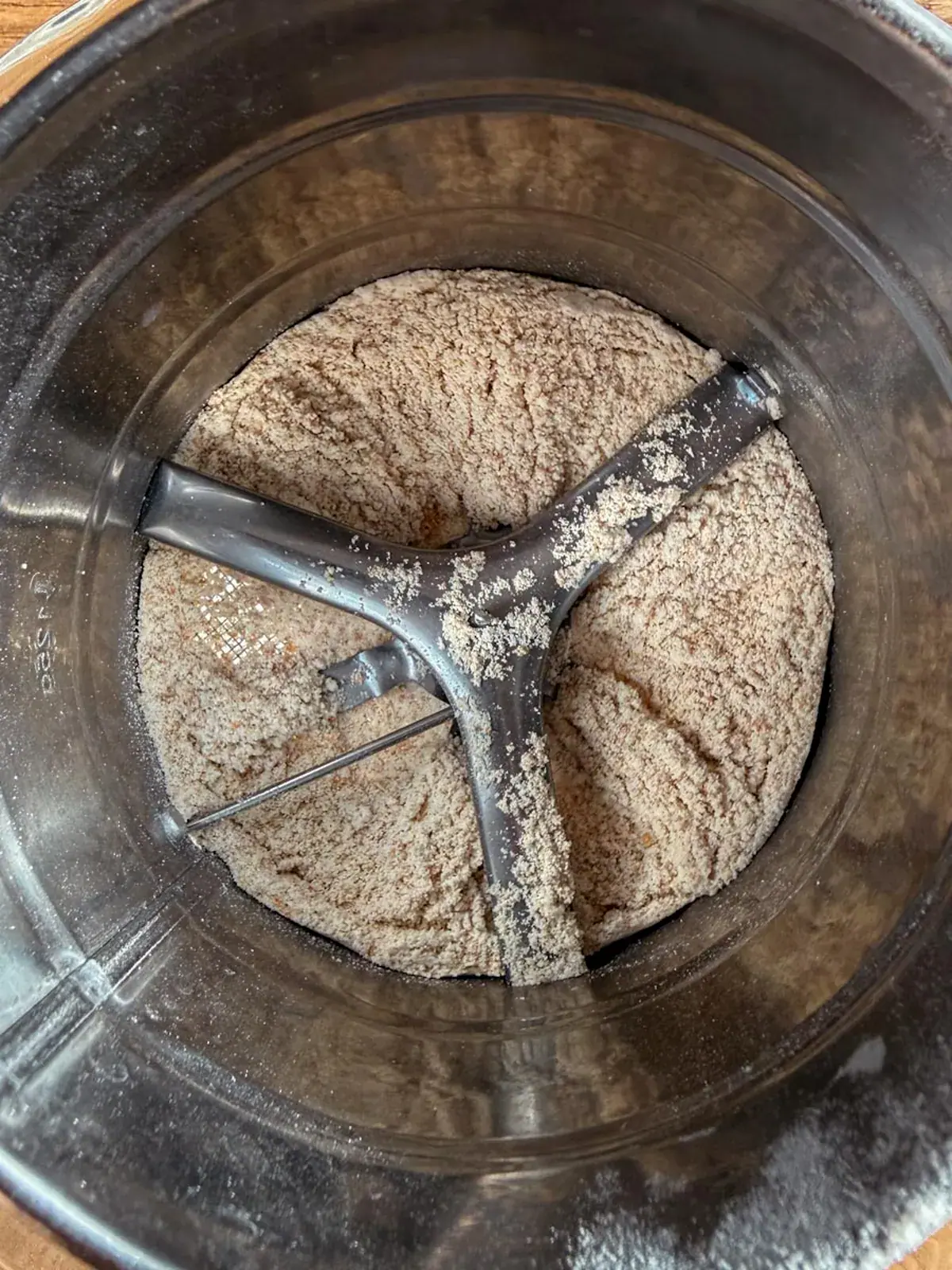 Close-up inside a hand sifter showing fresh milled flour with bran specks around the turning blades