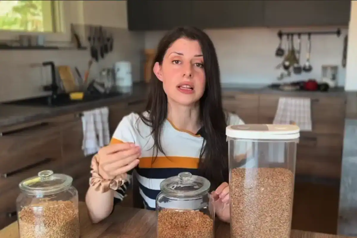 Baker showing different types of wheat berries stored in glass jars for home milling