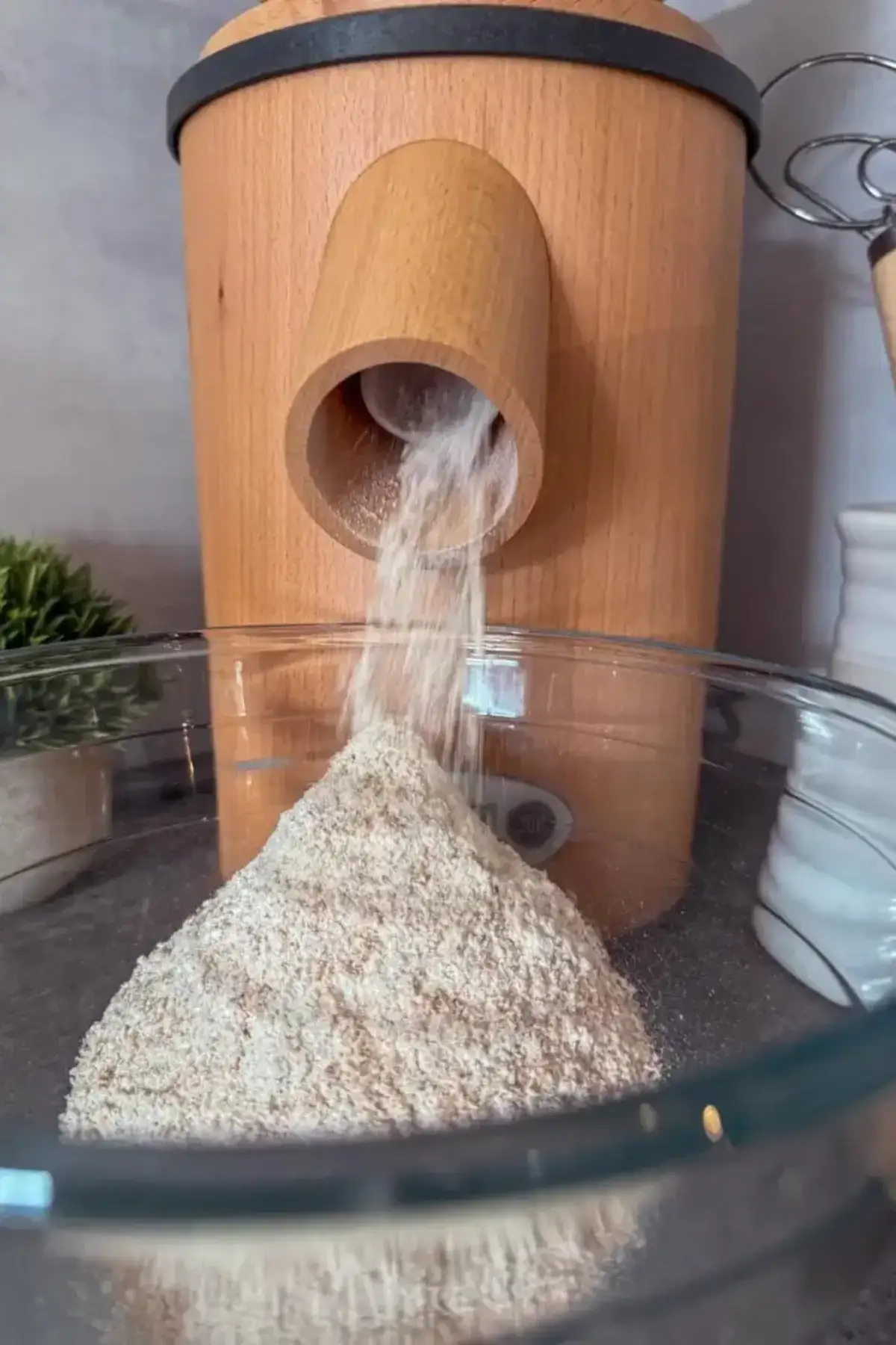 Freshly ground wheat flour flowing from the Mockmill Lino 200 chute into a glass bowl.